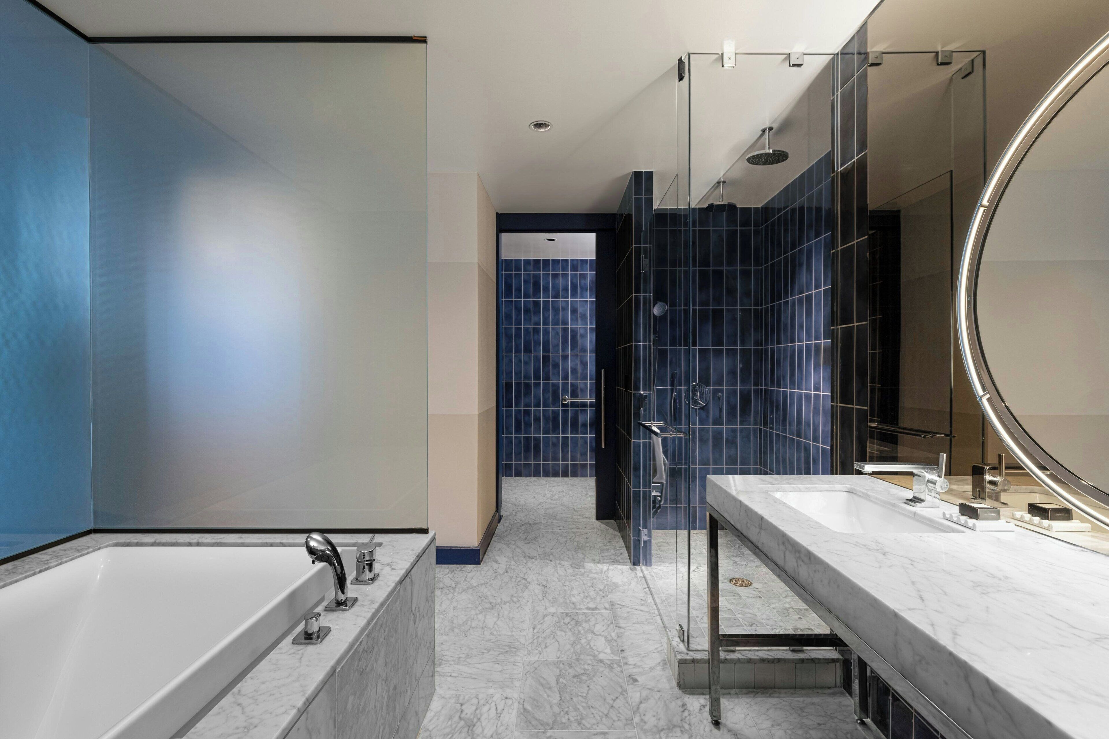 Une salle de bain moderne dotée d’une grande baignoire, d’une douche séparée et d’un meuble-lavabo avec un grand miroir.