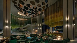 A modern lounge area with green seating, a bar, and a unique ceiling design. - W Hollywood (Los Angeles)