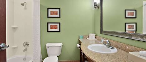 A bathroom with a bathtub, toilet, sink, and a large mirror.