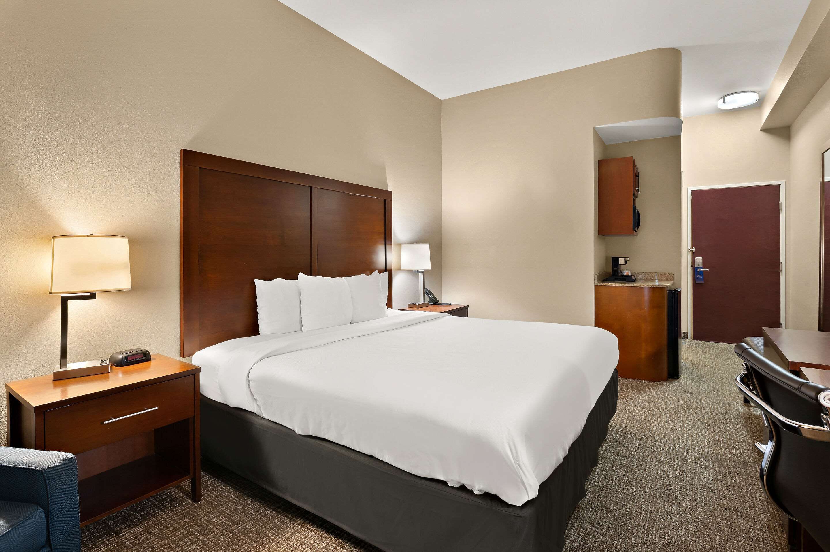 A hotel room with a large bed, bedside tables, a desk, and a chair.