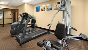 Gimnasio con cinta de correr, elíptica y máquina de pesas.