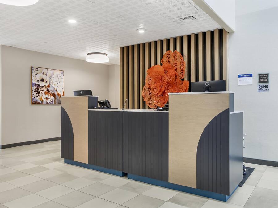 Taulell de recepció de disseny modern, un quadre abstracte gran a la paret i un senyal amb les indicacions d'entrada i sortida.