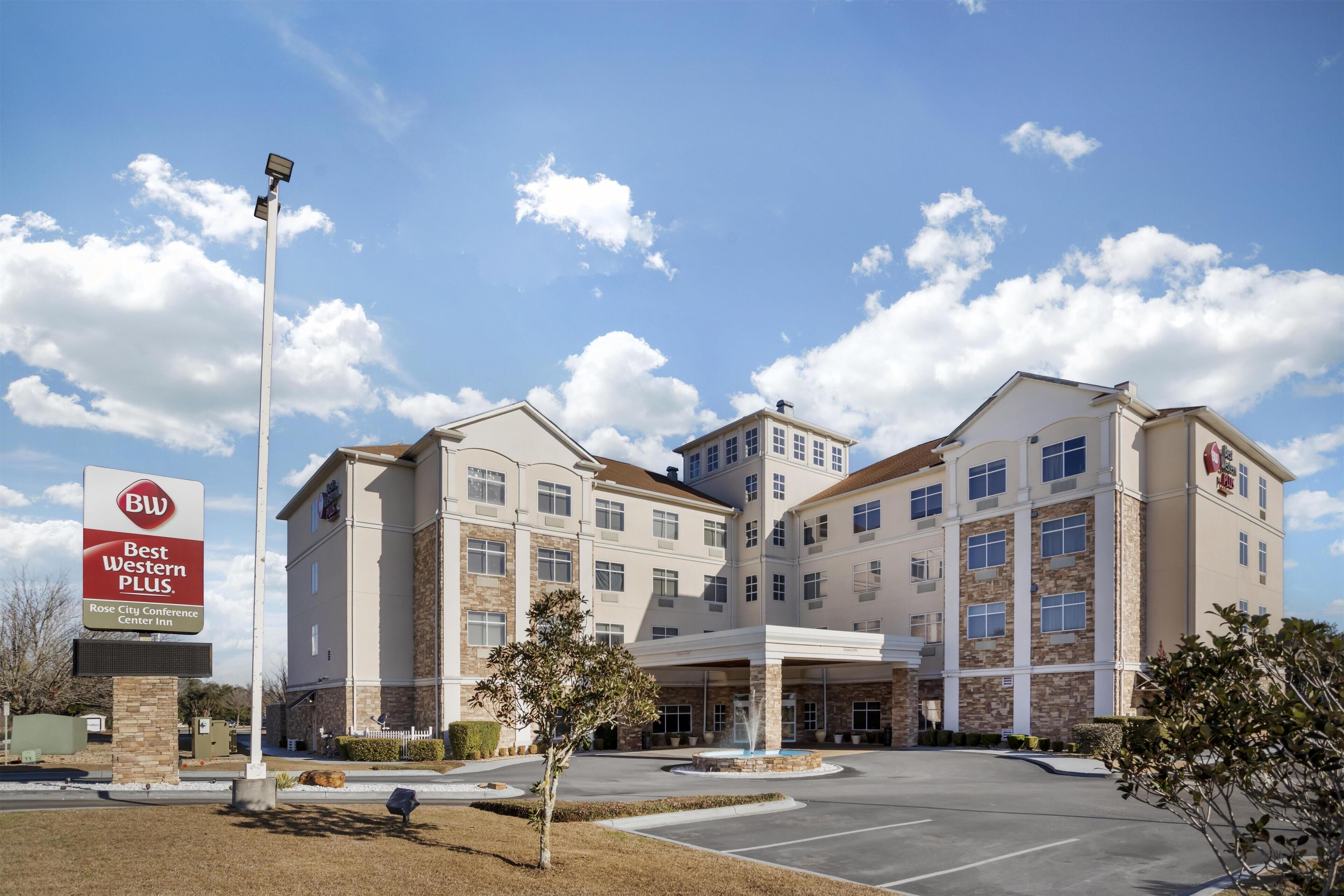 Um hotel Best Western Plus com um pátio central, várias entradas e céu claro.
