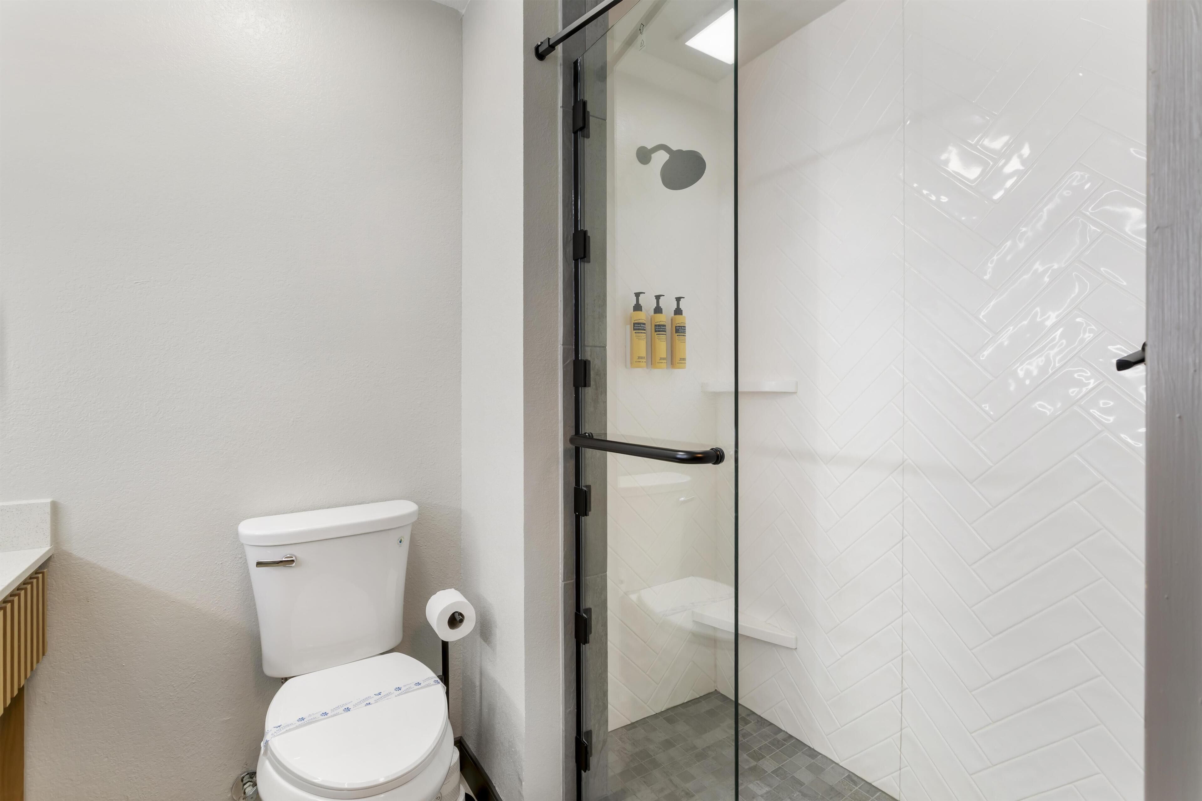 A modern bathroom with a glass shower enclosure, a toilet, and a white sink.