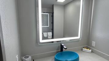 Une salle de bain avec un lavabo bleu, un miroir doté d’un éclairage à DEL et un porte-serviettes.