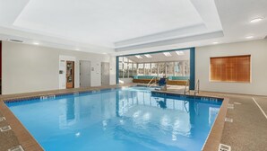 A large indoor swimming pool with clear water, a diving board, and a view of the outside through large windows. - Best Western Plus Rose City Conference Center Inn (Thomasville)