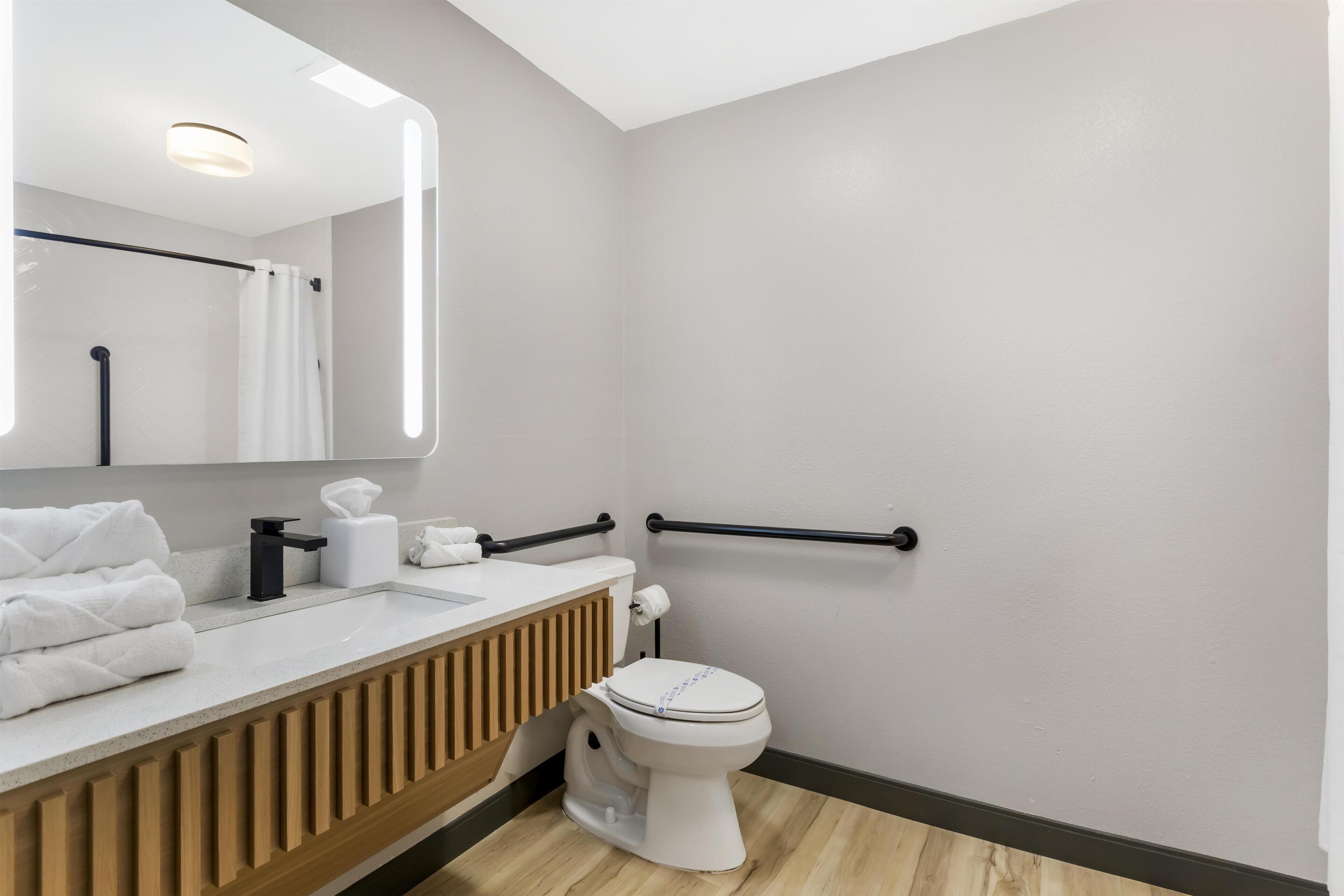 Une salle de bain moderne avec des toilettes, un lavabo et un miroir.