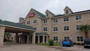 A Red Roof Inn & Suites building with a covered entrance, multiple windows, and a parking area with a blue handicapped parking space. - Red Roof Inn & Suites Midland (Midland)