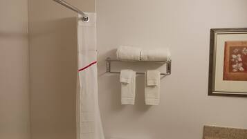 Un baño con cortina de ducha, un toallero con dos toallas y un cuadro en la pared.