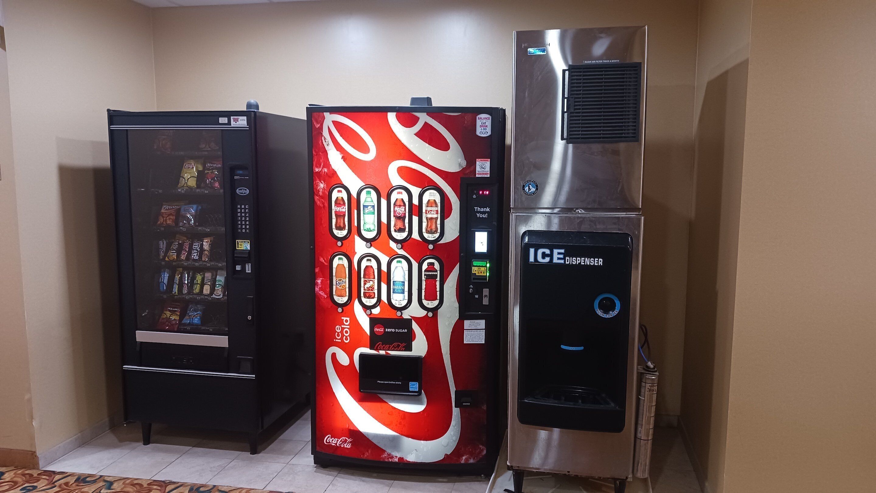 A vending machine with a Coca-Cola logo, a beverage vending machine, and an ICE dispenser.
