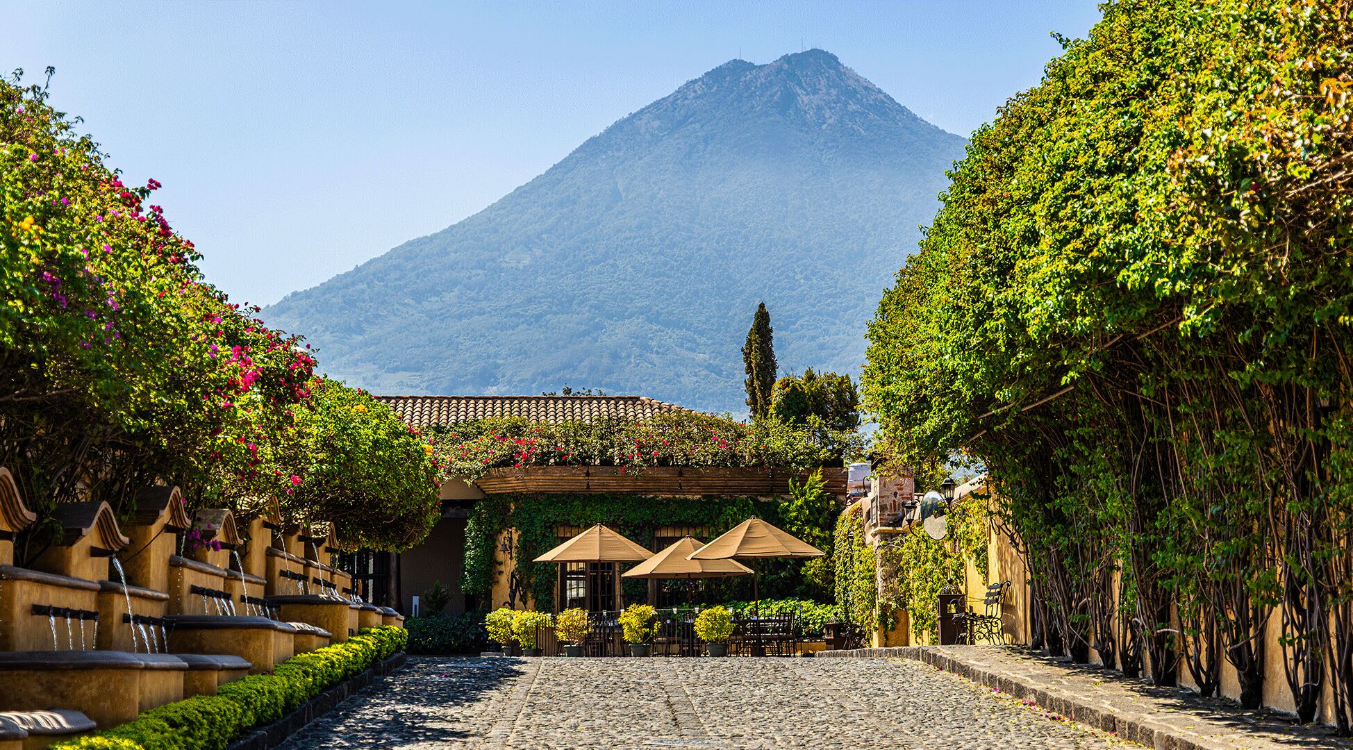 Una strada acciottolata che conduce a un edificio con una montagna sullo sfondo.