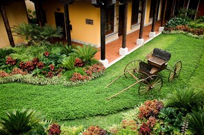 A courtyard with a carriage, lush greenery, and a building with columns. - Hotel Camino Real Antigua (Antigua Guatemala)
