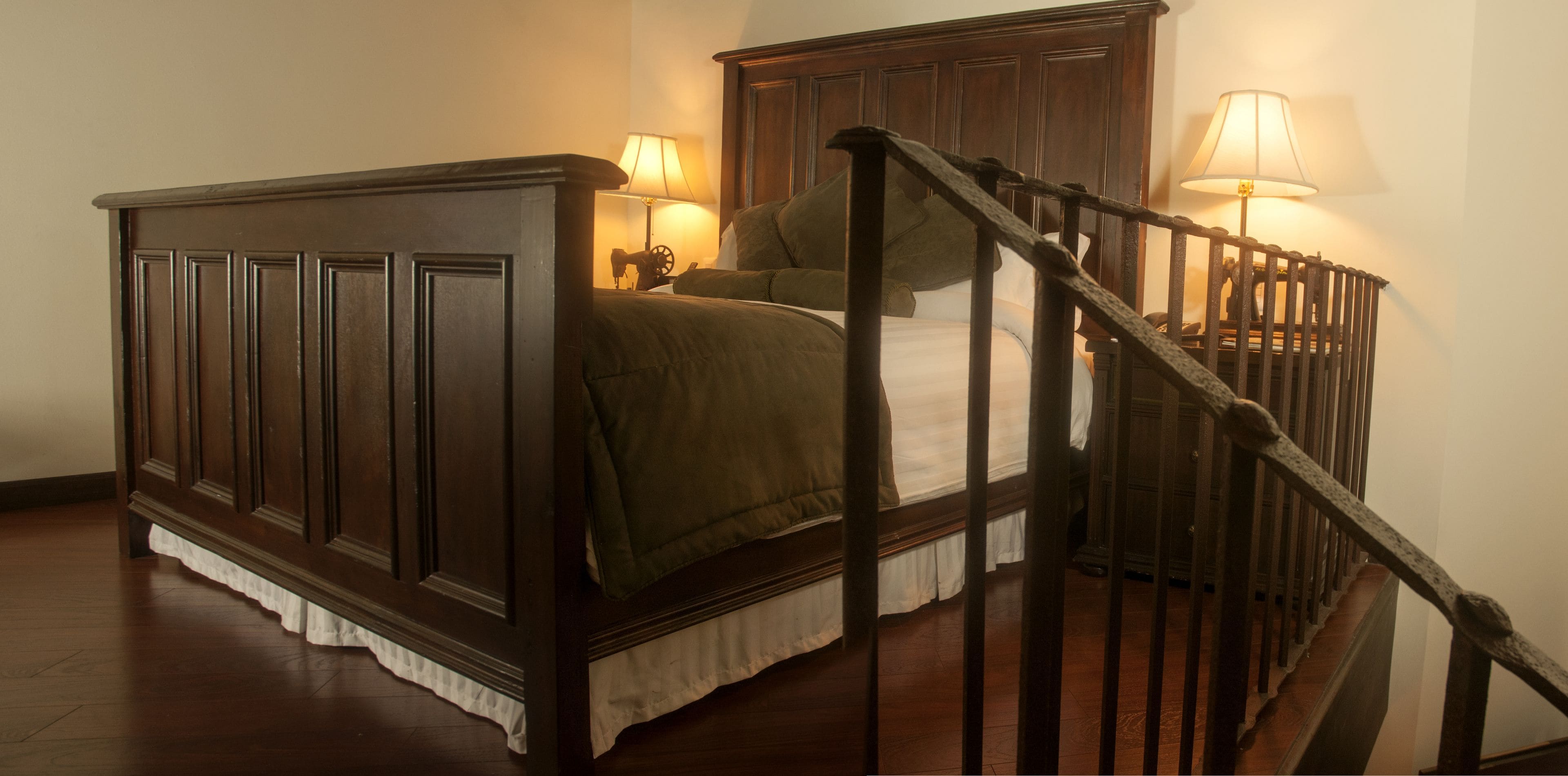 A bedroom with a wooden bed, a staircase, and two bedside lamps.