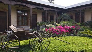 A courtyard with a wooden carriage, a well-maintained garden, and a building with a traditional architectural style.