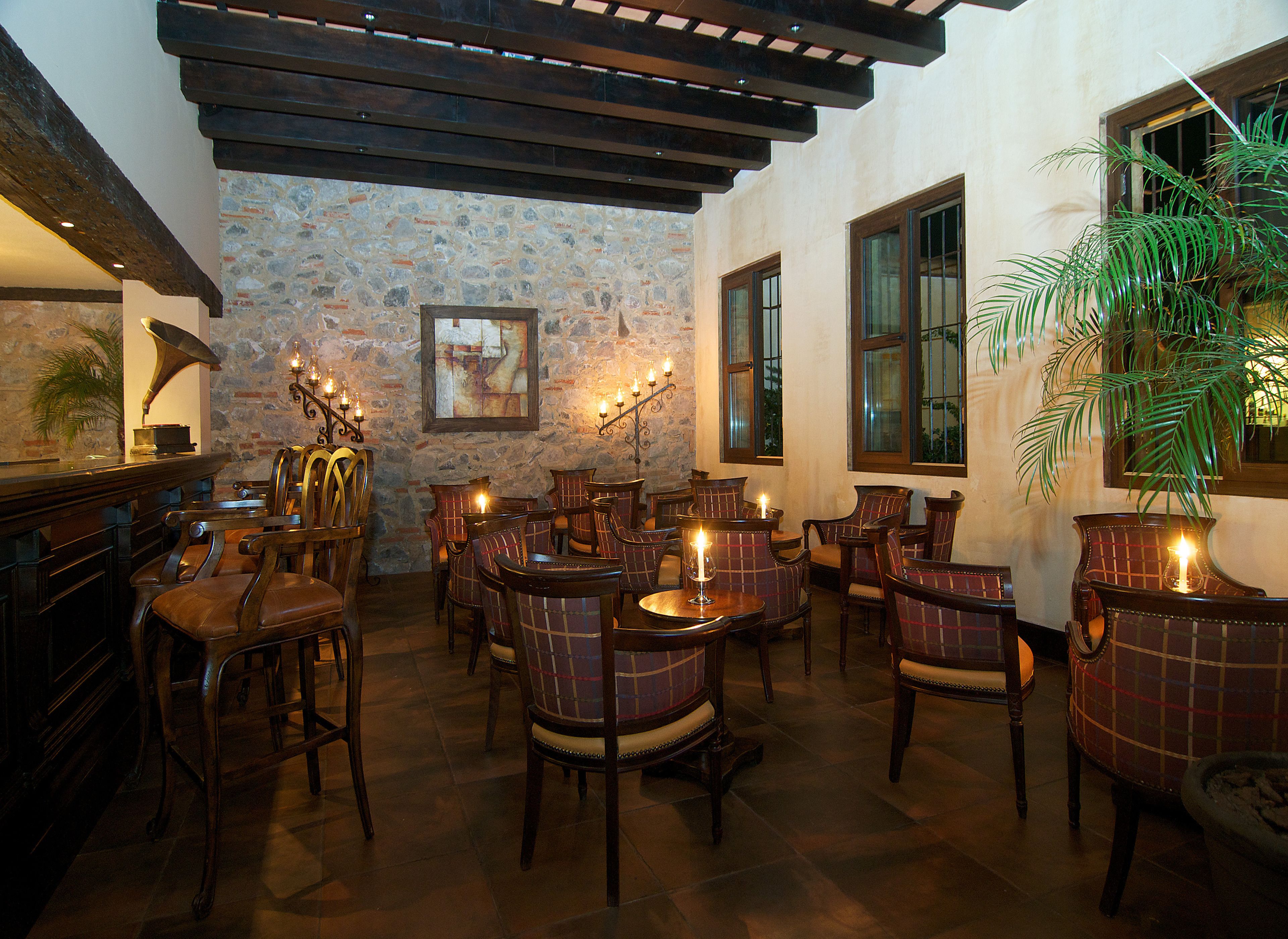 Un restaurante acogedor con mobiliario de madera, paredes de piedra y ventanas amplias.