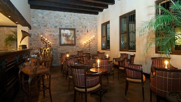 Un restaurante acogedor con mobiliario de madera, paredes de piedra y ventanas amplias.
