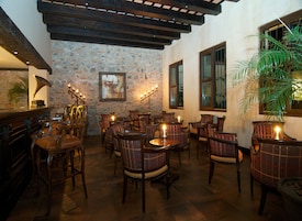 Un restaurante acogedor con mobiliario de madera, paredes de piedra y ventanas amplias.