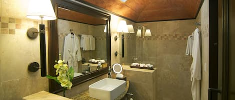 A bathroom with a large mirror, a sink, a shower, and a towel rack.