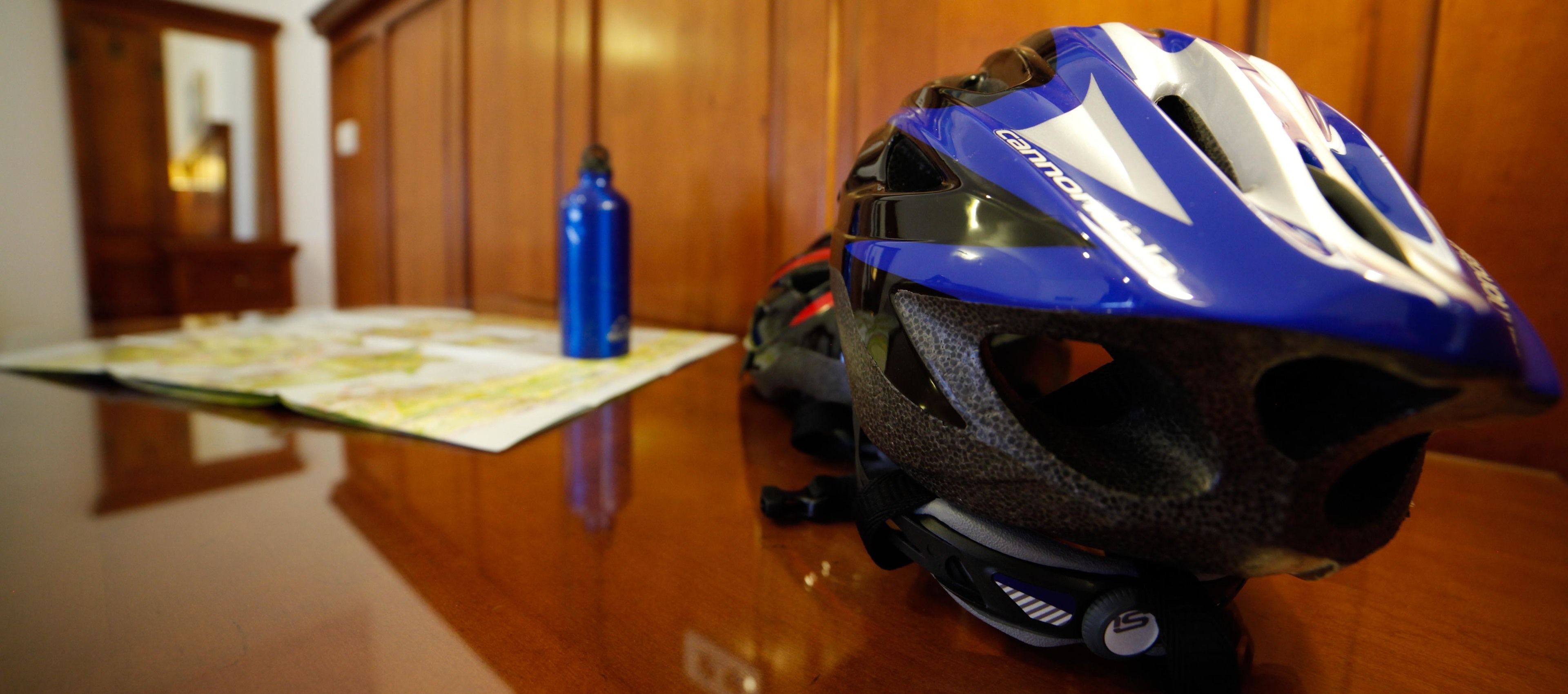 Een blauw-witte helm op een houten tafel, samen met een kaart en een blauwe fles.