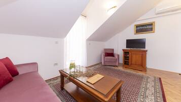 A living room with a sofa, a coffee table, a TV, and a chair.