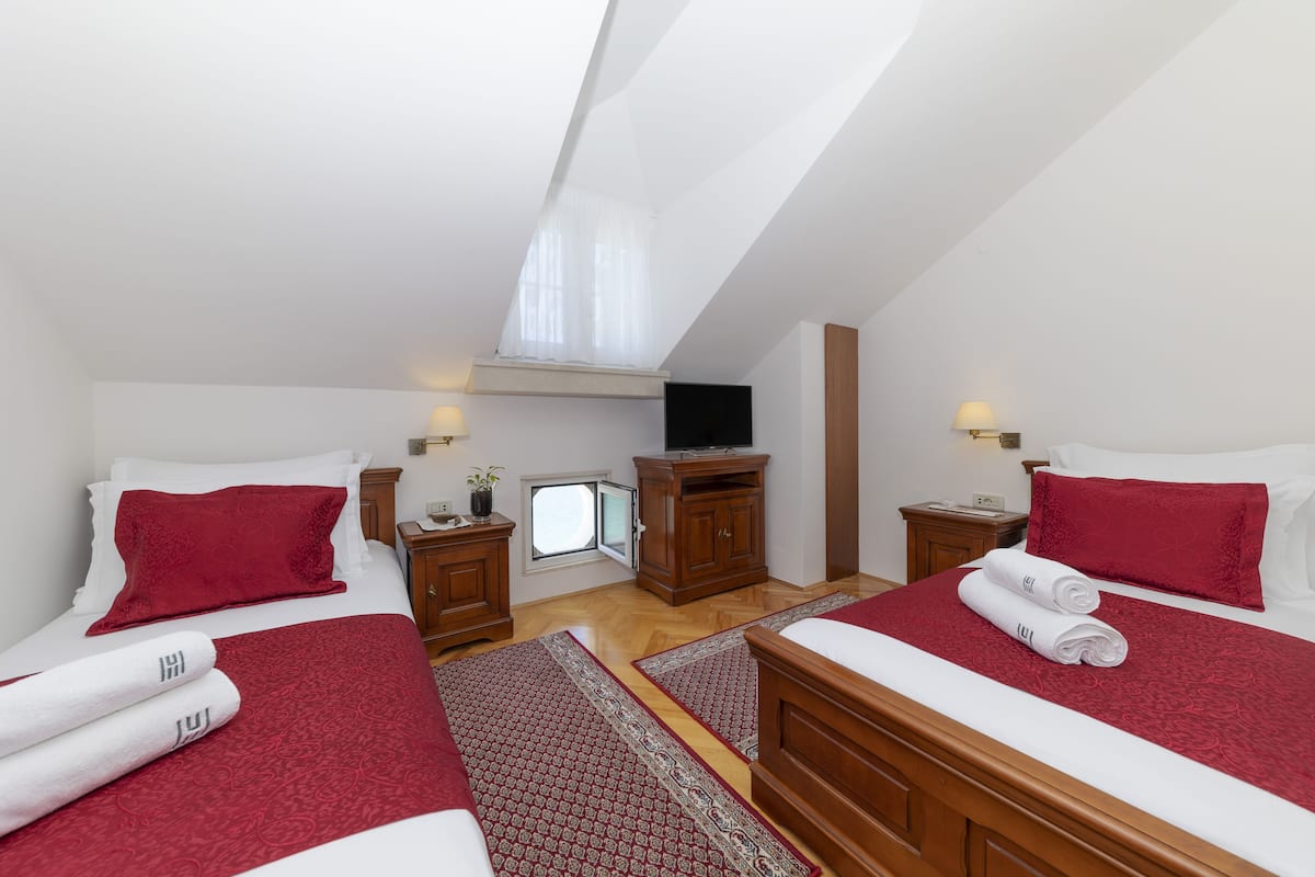 Ett hotellrum med två sängar, en TV, ett litet bord och ett fönster.