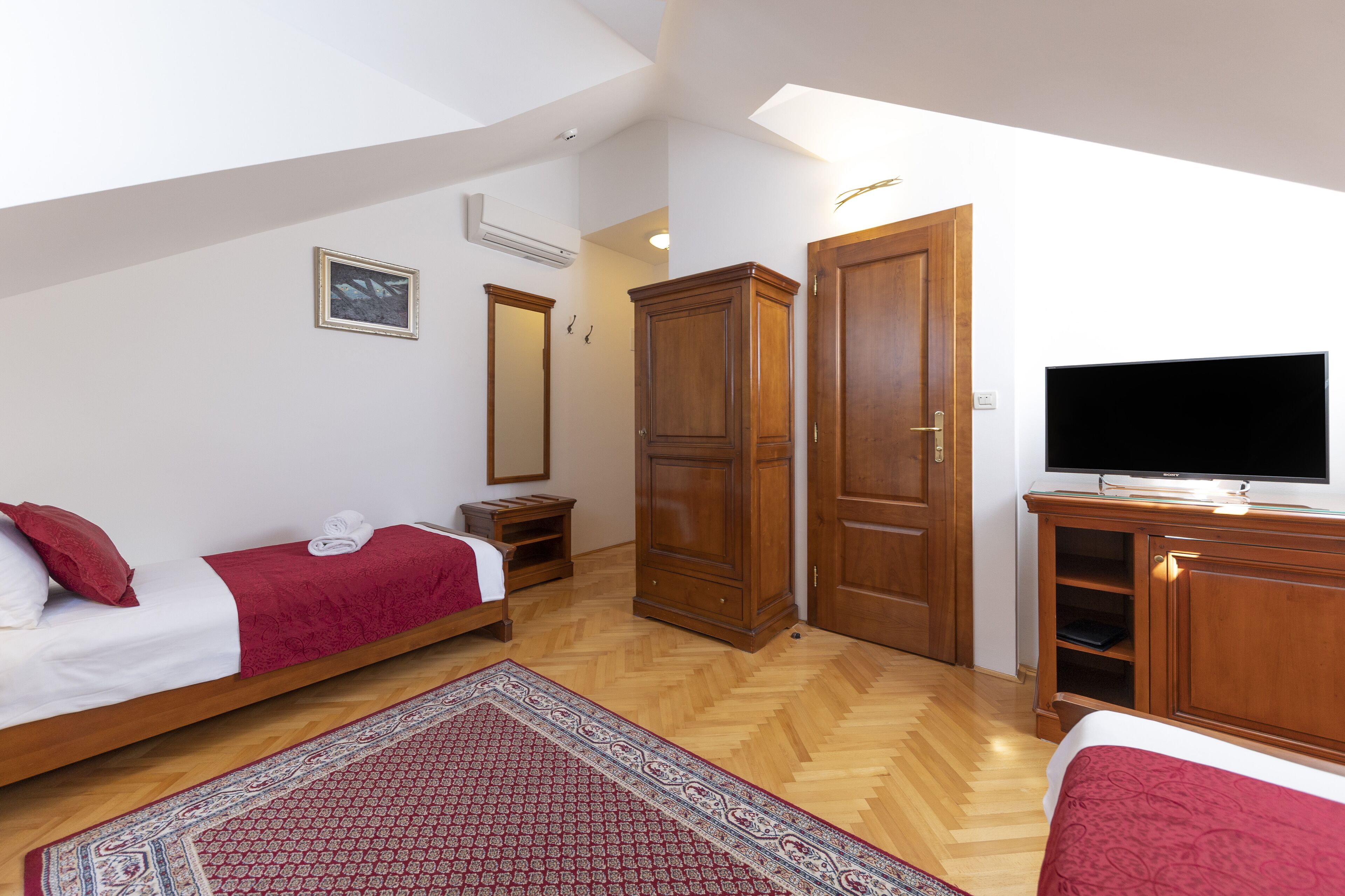 Una camera da letto con un letto, una TV, un armadio e uno specchio.