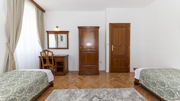 Un dormitori amb dos llits, un armari de fusta, un escriptori amb una cadira i un mirall.