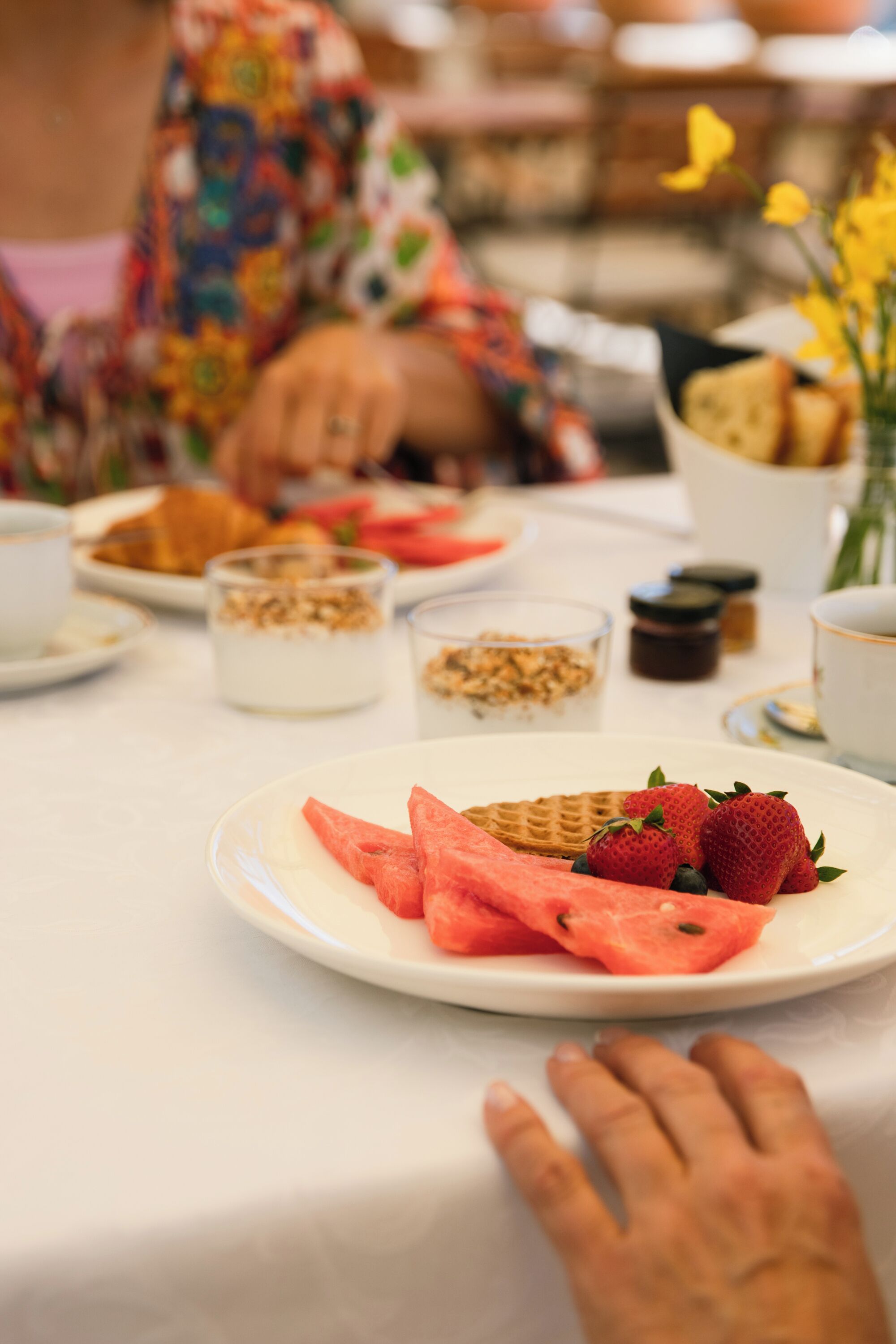 A dining table with plates of food, including strawberries and watermelon slices.