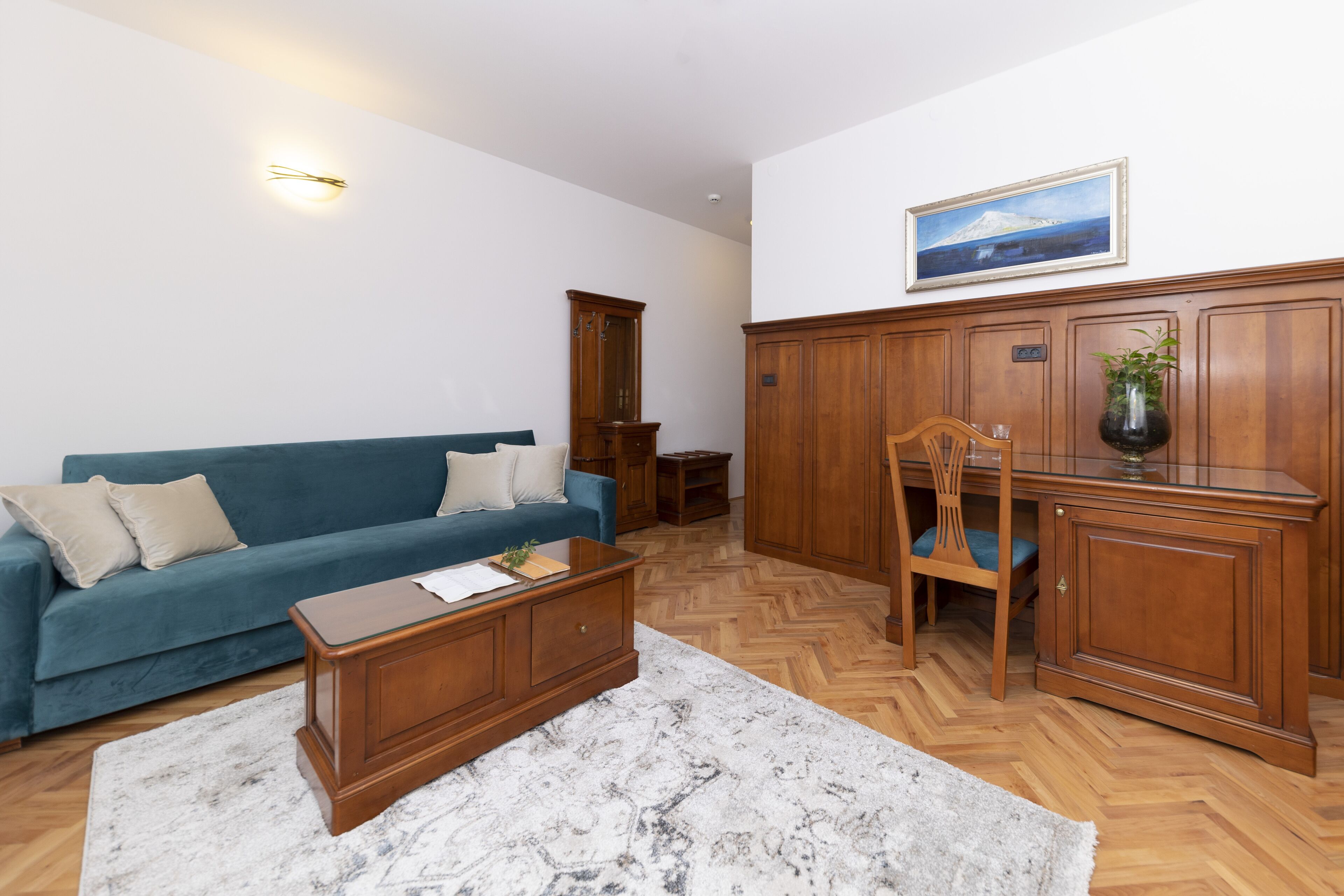 Una sala de estar con sofá azul, mesa de centro de madera y piso de madera en patrón de espiga.
