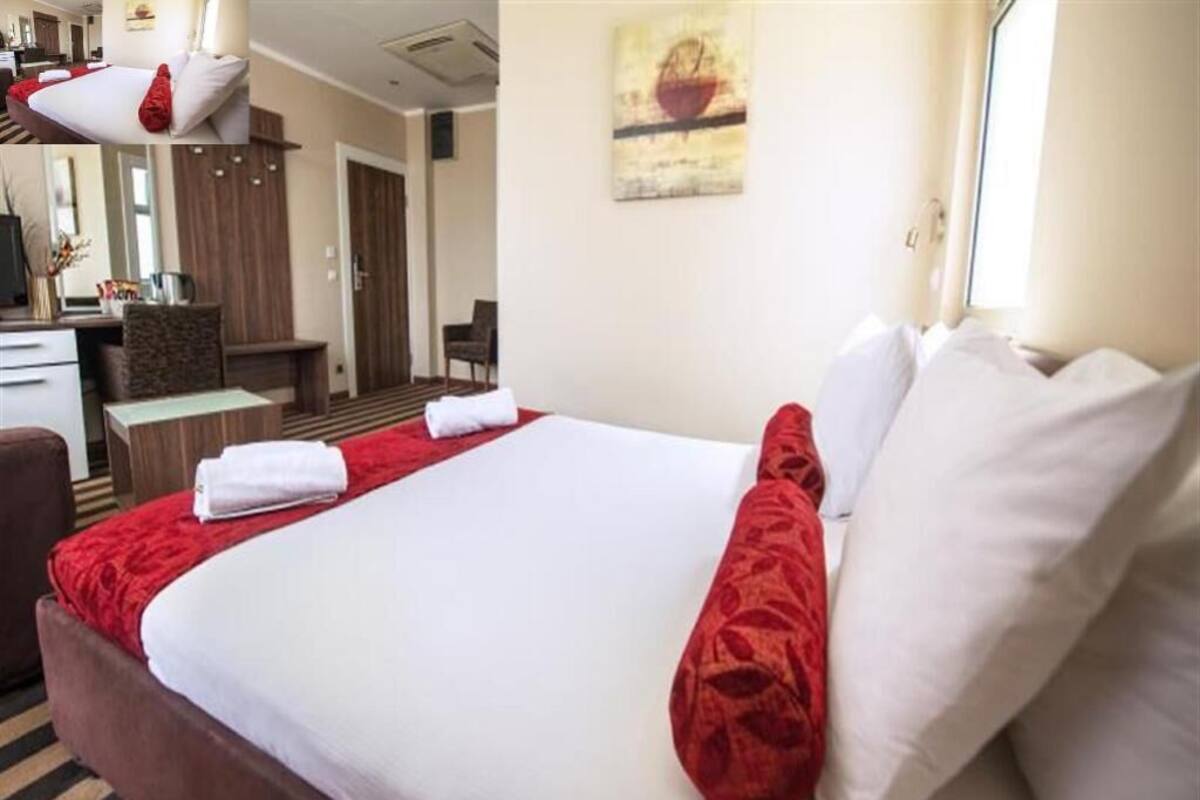 Une chambre d’hôtel avec un lit, un bureau, une chaise, une armoire et un tableau au mur.