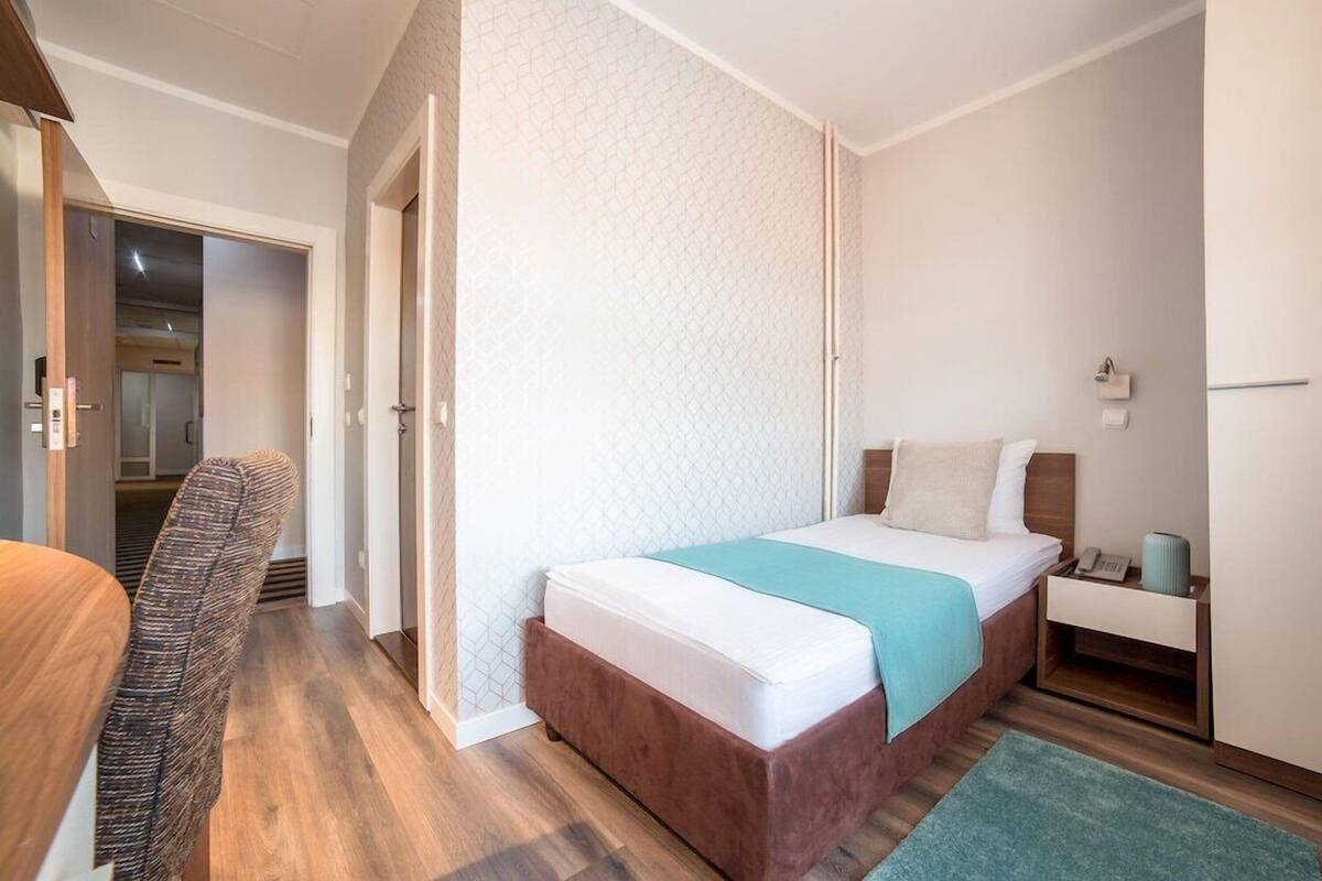 Une chambre d’hôtel avec un lit, une table de chevet et une chaise.