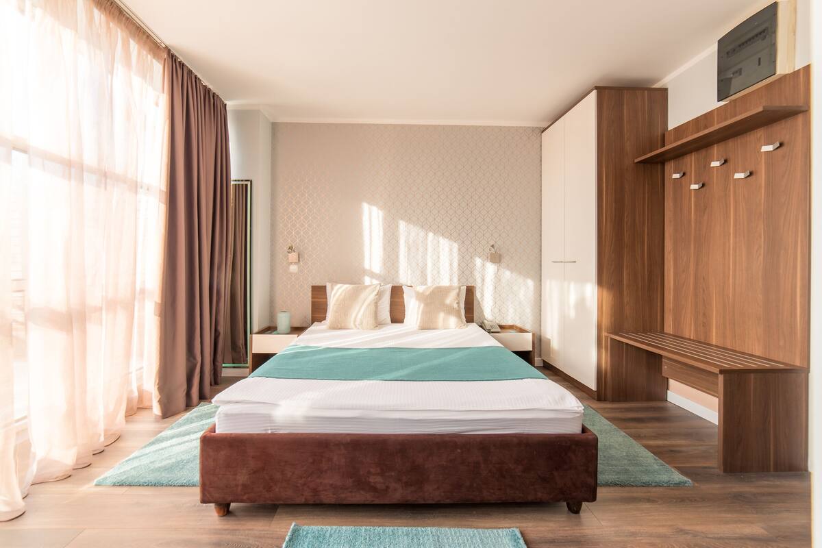Une chambre à coucher moderne avec un grand lit, une armoire en bois et un banc.