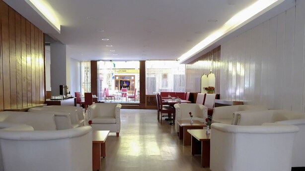 A spacious lobby with white sofas and armchairs, a coffee station, and a view of the dining area. - Kıspet Konak Hotel (Çanakkale)