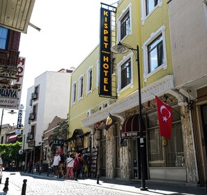 A yellow building with a sign for 'KISPET HOTEL' and a flag. - Kıspet Konak Hotel (Çanakkale)