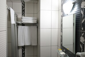 A bathroom with white tiled walls, a glass shower enclosure, and a mirror with floral designs. - Kıspet Konak Hotel (Çanakkale)