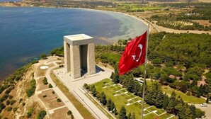 A coastal building with a flag, surrounded by greenery and a clear view of the sea. - Kıspet Konak Hotel (Çanakkale)