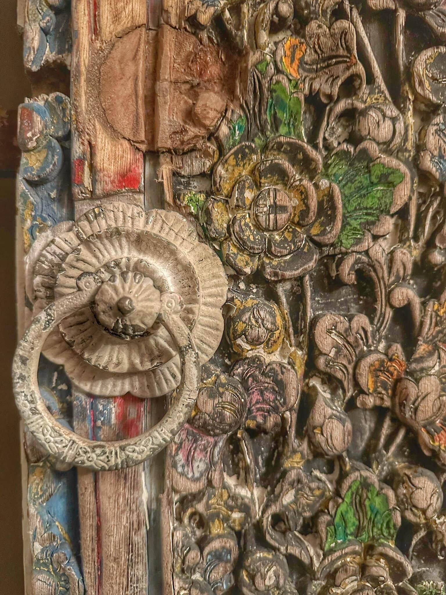 Una puerta detallada y ornamentada con tallas intrincadas y un tirador decorativo.