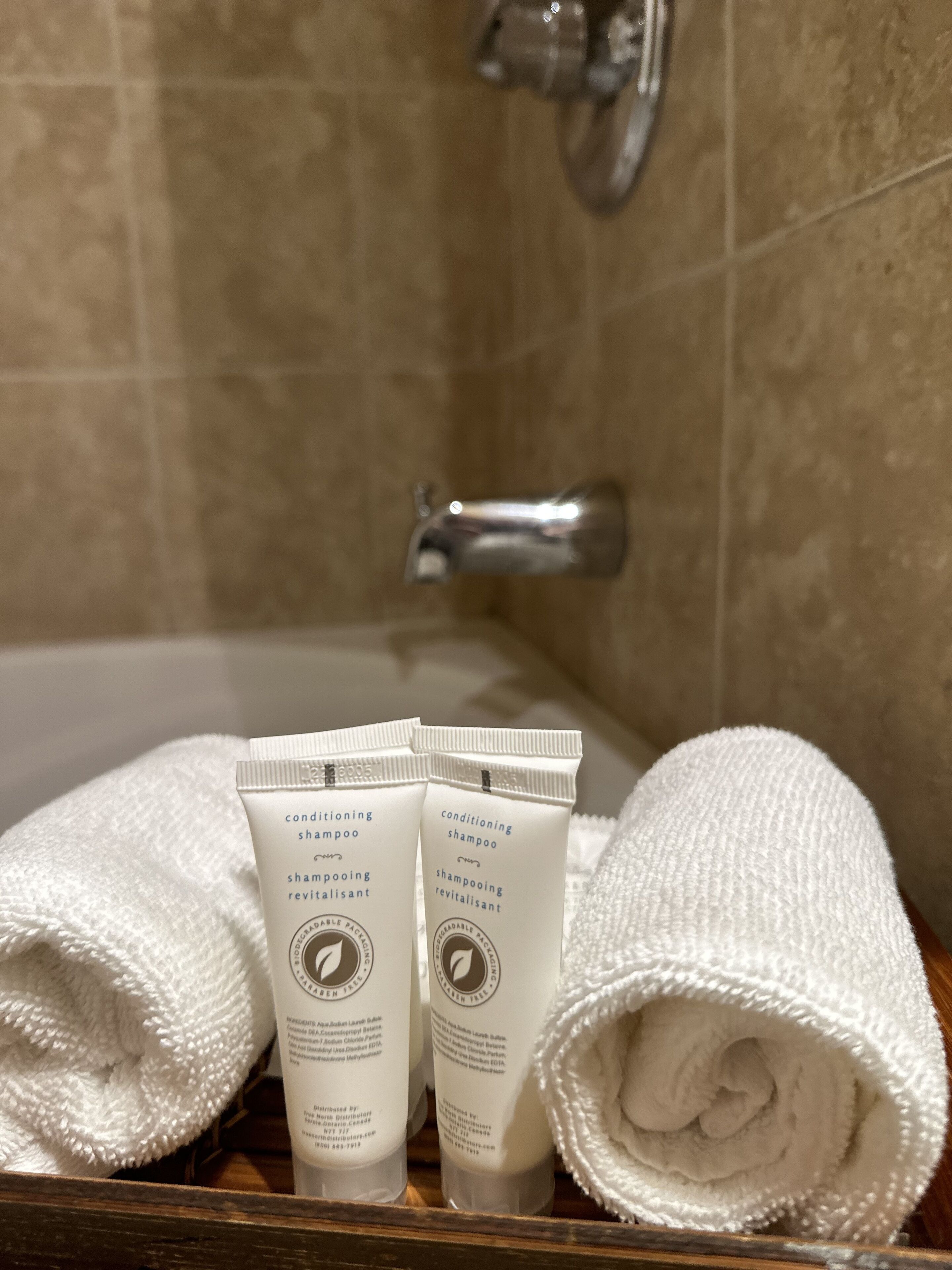 Un baño con una bañera, dos botellas de champú y dos toallas enrolladas.
