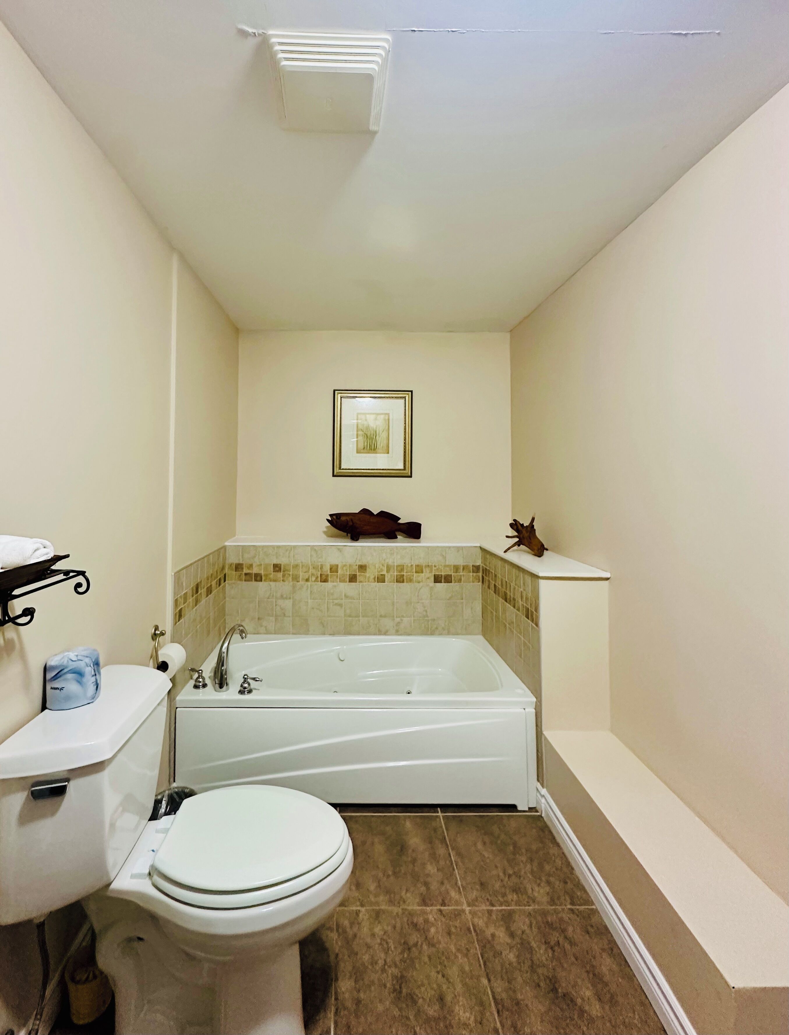 A bathroom with a toilet, sink, bathtub, and a framed picture on the wall.