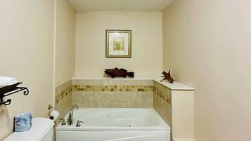 A bathroom with a toilet, sink, bathtub, and a framed picture on the wall.