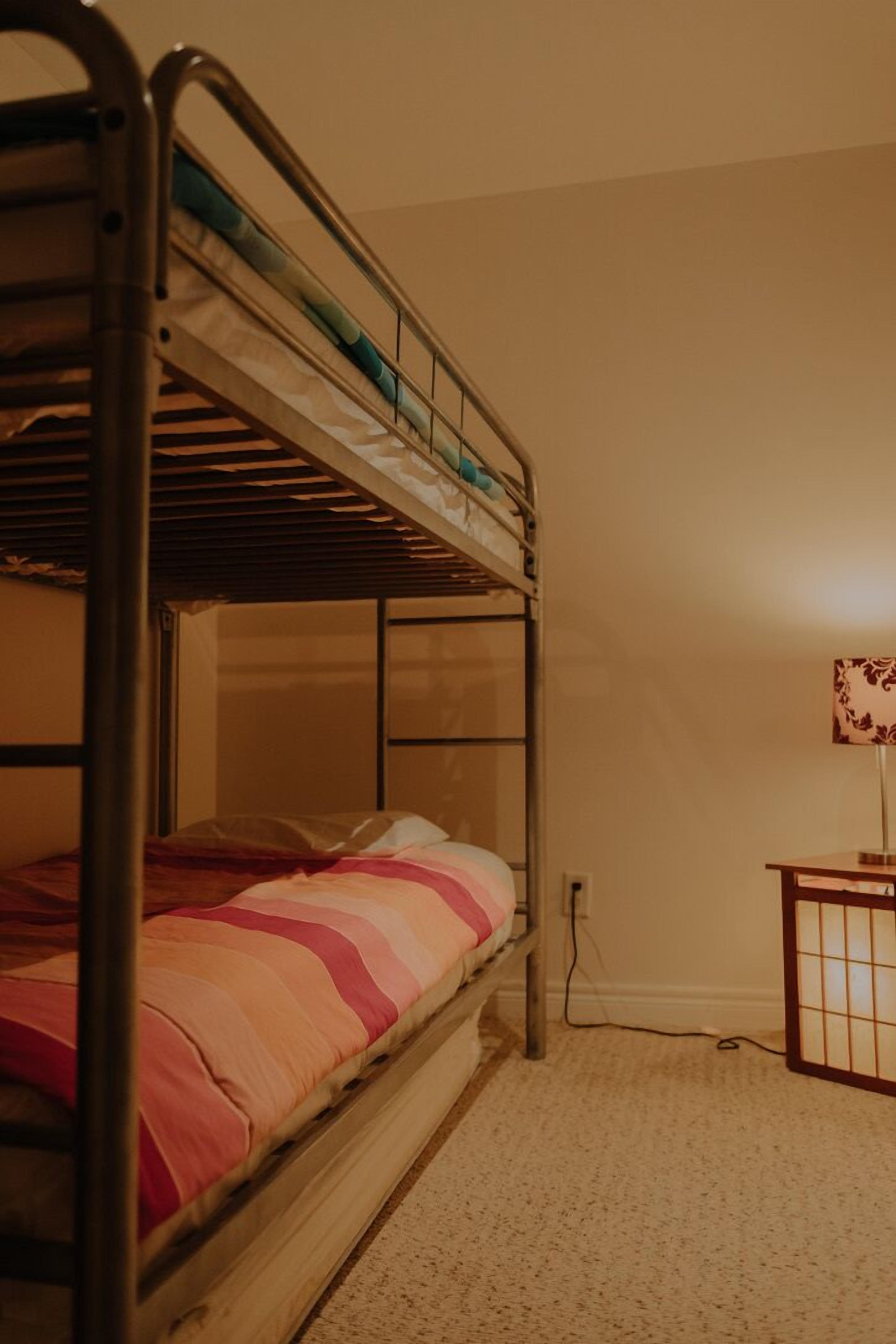 A bunk bed with a wooden frame and a mattress with a striped blanket.