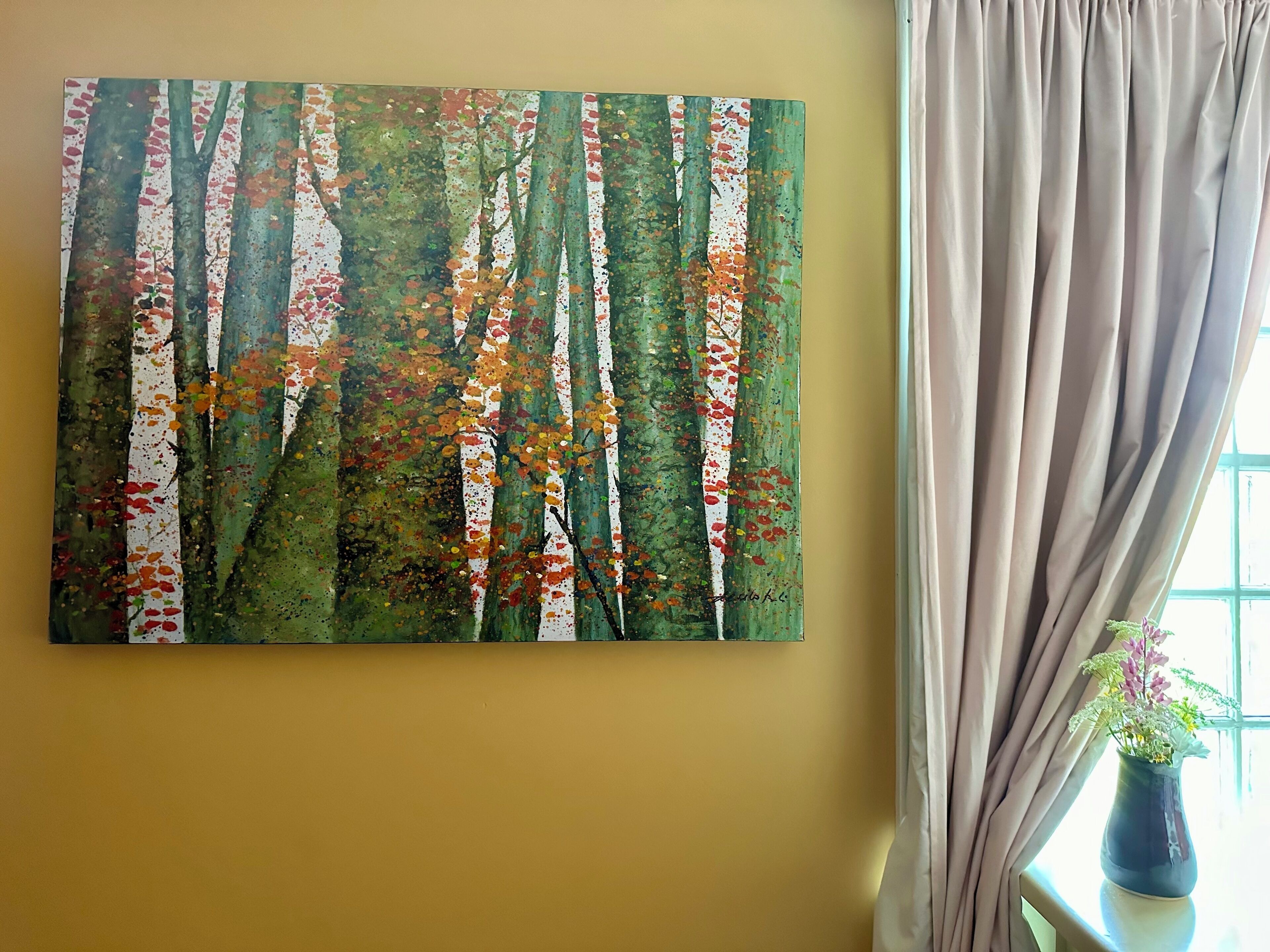 A painting of a forest with trees and autumn leaves on a yellow wall.