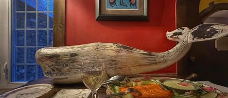 Une table avec un plat de saumon, un verre à vin et une sculpture décorative en forme de tête de baleine.