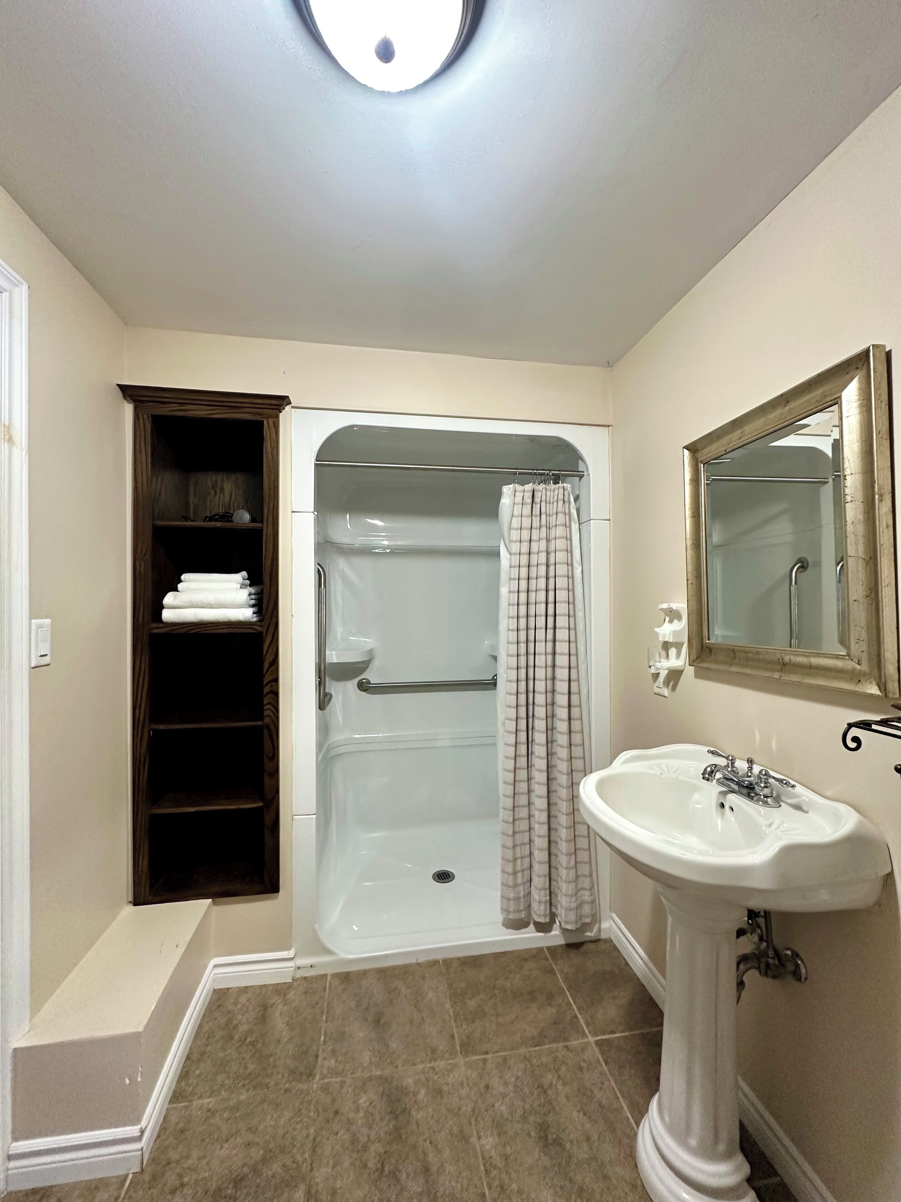 A bathroom with a walk-in shower, a vanity with a sink, and a towel rack.