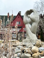 A stone sculpture in a garden with a red building in the background.