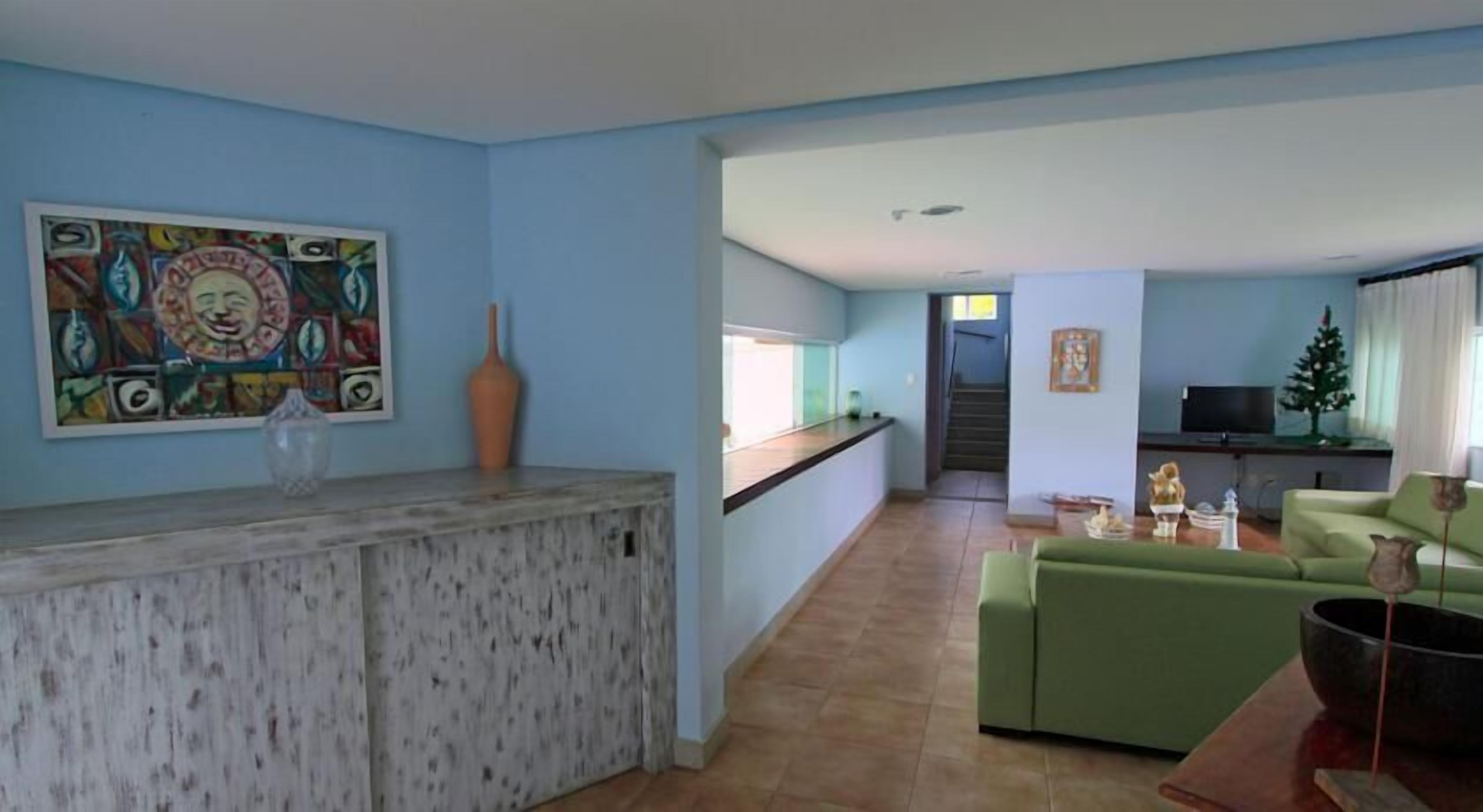 A spacious living area with a green sofa, a kitchen counter, and a staircase leading to an upper floor.