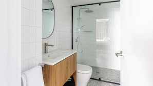 A modern bathroom with a glass-enclosed shower, a wooden vanity, and a white toilet. - Royal Exhibition Hotel (Surry Hills)