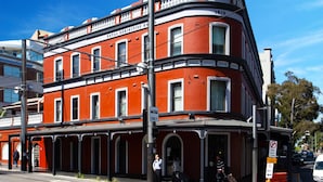 A red building with a balcony and arched windows, labeled "E.R." and "ROYAL EXHIBITION HOUSE." - Royal Exhibition Hotel (Surry Hills)