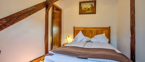 Una habitación con estructura de madera, una cama, un cuadro en la pared y una lámpara en el techo.