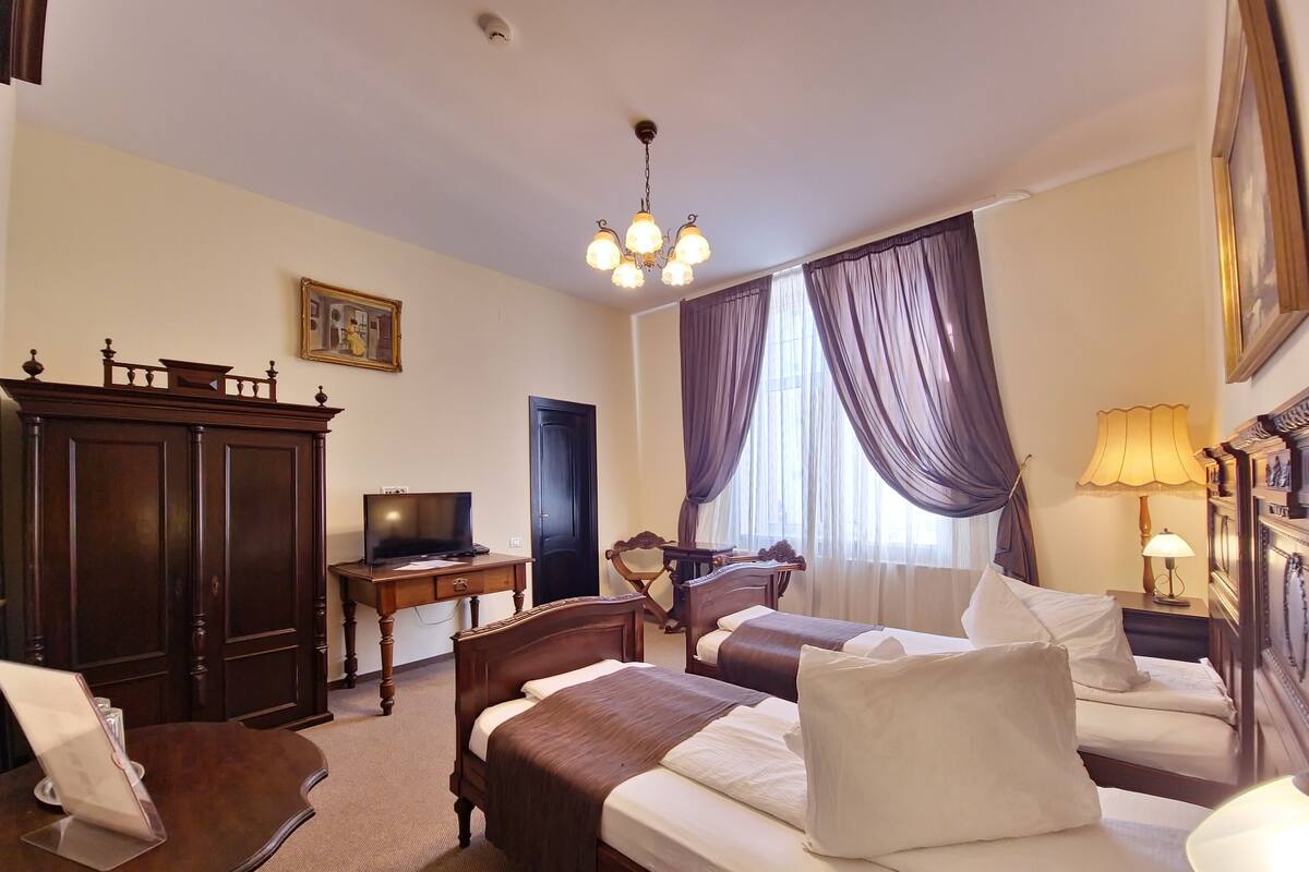 Une chambre d’hôtel avec deux lits, un bureau avec une télévision, une chaise, une lampe et une armoire.